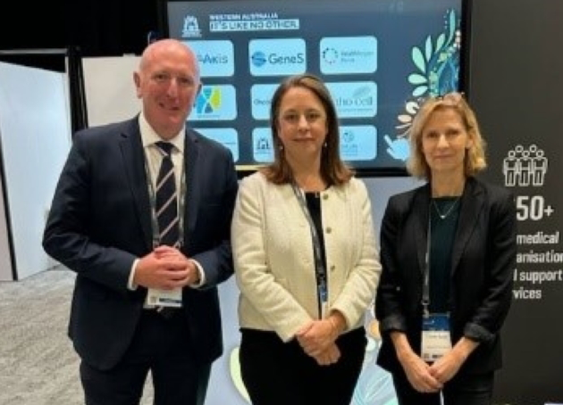 A man and two women standing in front of a display booth at AusMedtech 2025