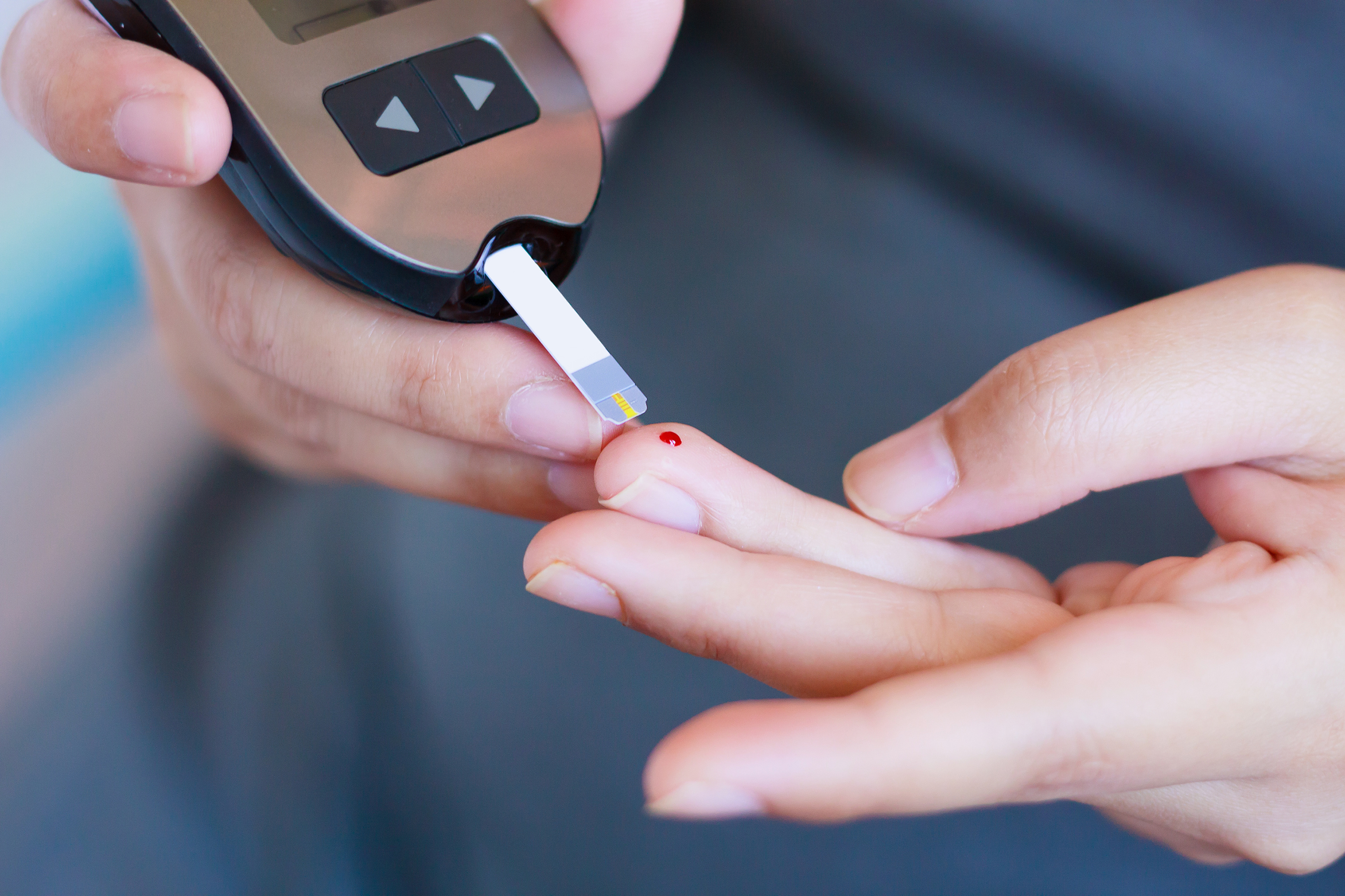 Close-up of person's hands doing blood glucose test