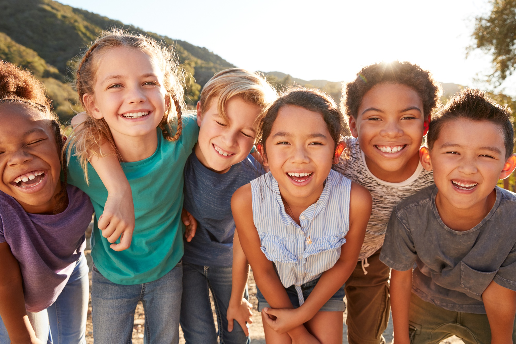 group of six children crouched together smiling at the camera