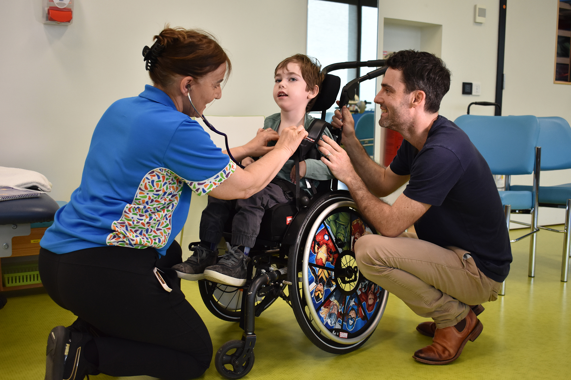 Nurse tending to small child in wheelchair with father 